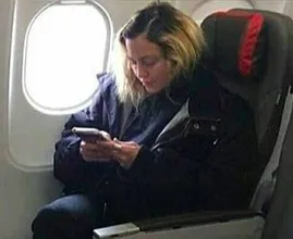 This 'normal' airplane passenger is actually a world famous singer! Do you see who it is?